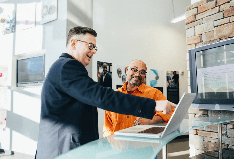 Trade show exhibitor pointing to his laptop to explain his product to a client.
