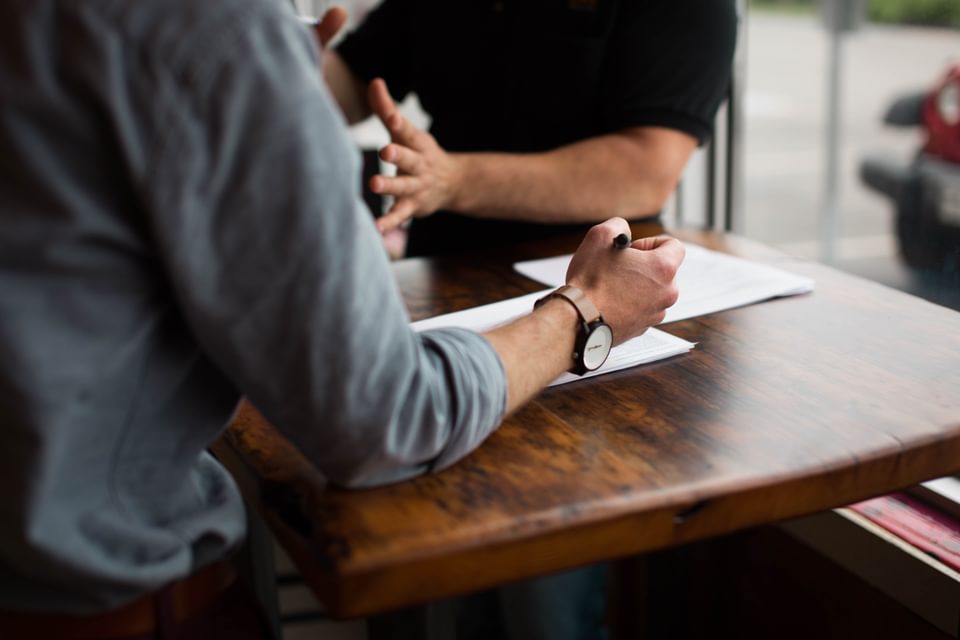 Two professionals sitting at a table discussing a potential project.